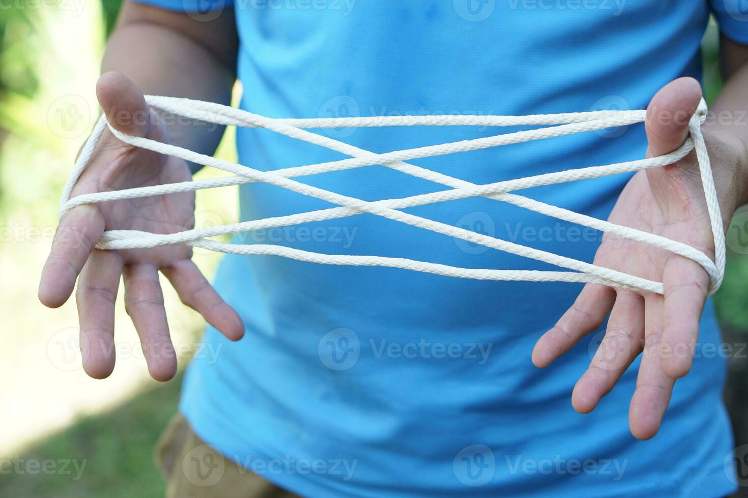 Closeup man hands is playing rope which called cats cradle game. Concept, game involving the creation of various style figures between the fingers. Traditonal playing. photo