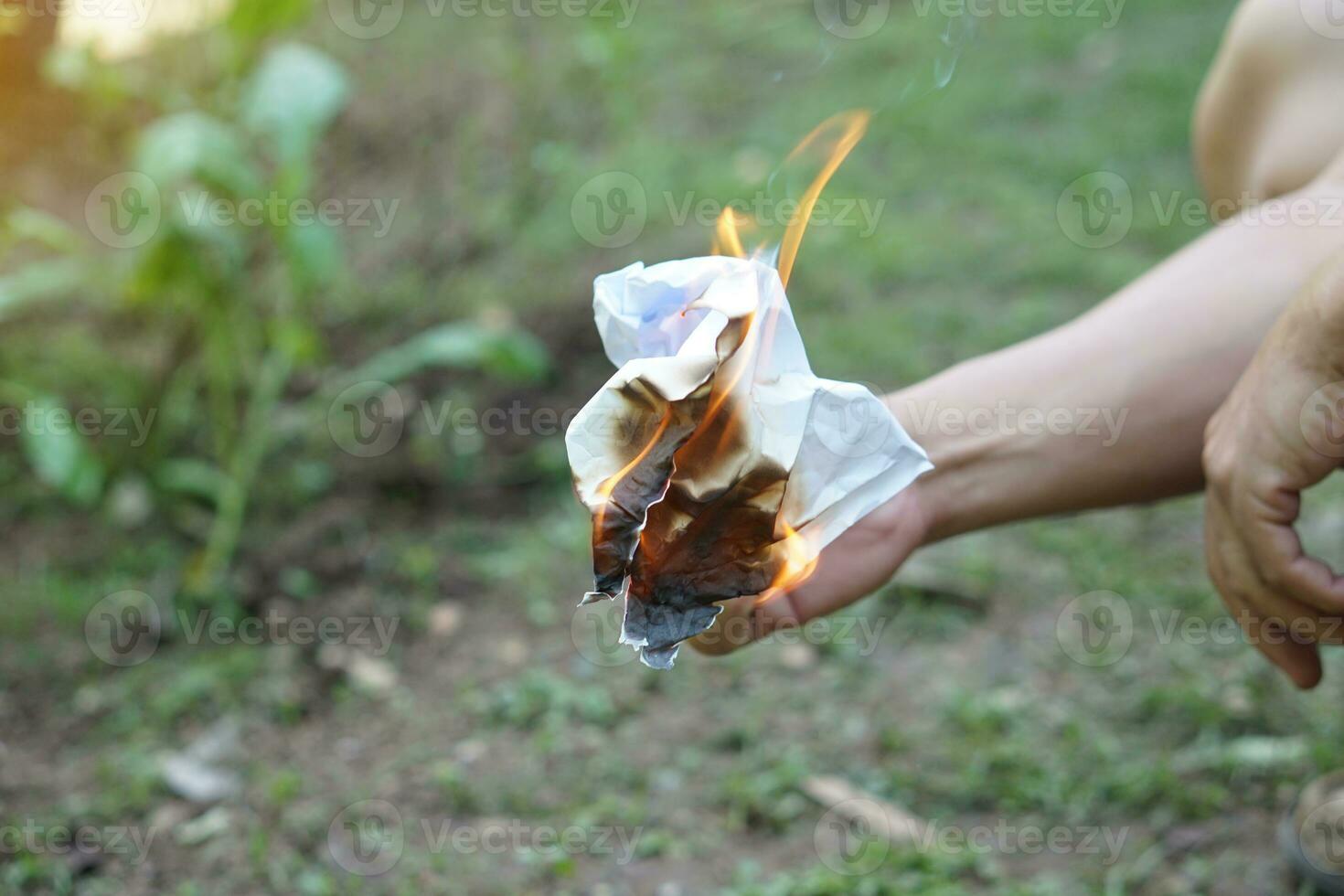 Close up hand hold fire burning on paper. Concept, destroy document, secret or evidences by fire. Start lighting fire. Careless fire-setting is dangerous, cause fire tragedy. photo