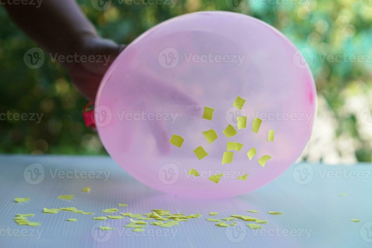 Closeup hand hold pink balloon to do science experiment about static electricity from balloon and pieces of paper. Concept, Science lesson, fun and easy experiment. Education. Teaching aids. photo