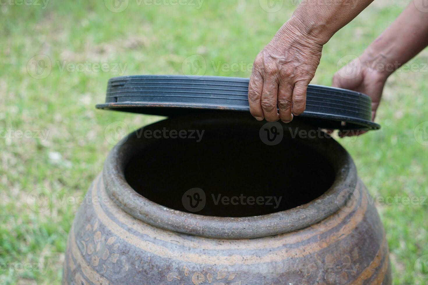Closeup hands hold lid to cover water jar to protect from mosquitoes to breed inside or other  insects or dust go into water. Concept, campaign to stop mosquitoes cycle to lay eggs in water container photo