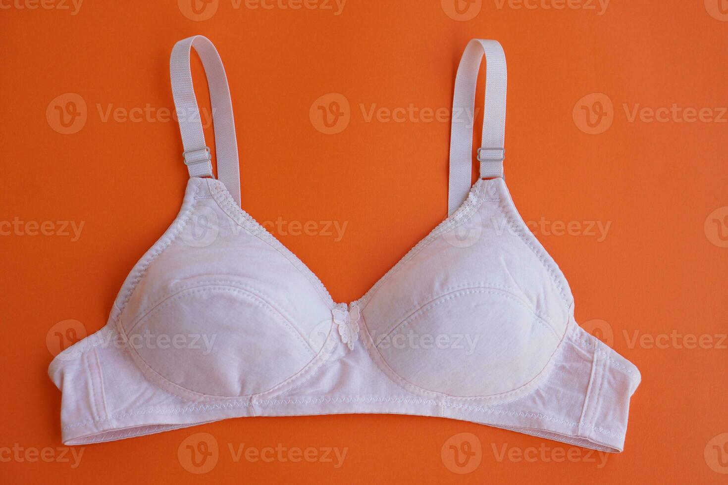 White bra on orange background.Concept, feminine brassiere. Classic comfortable with cup A for female young teenagers. Protect and hold beautiful breasts. Breast cancer awareness. photo