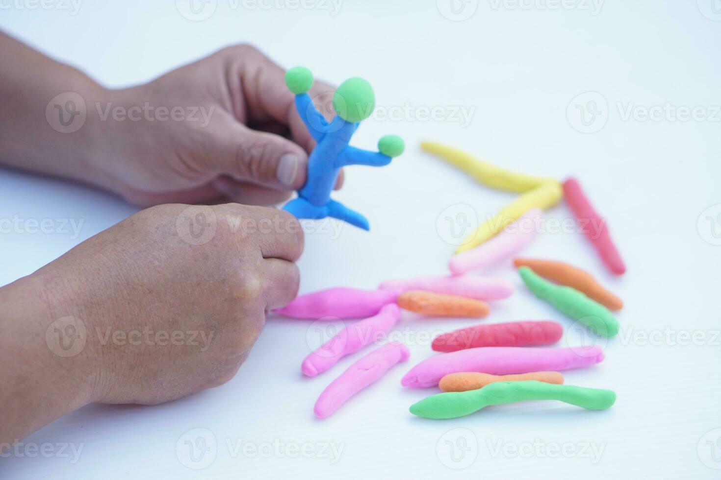 Close up man hands holds small colorful plasticine dough bars to make figures. Concept, alzheimer, weak muscle patients recovering activity by sculpting. Make concentration. Develop imagination. photo