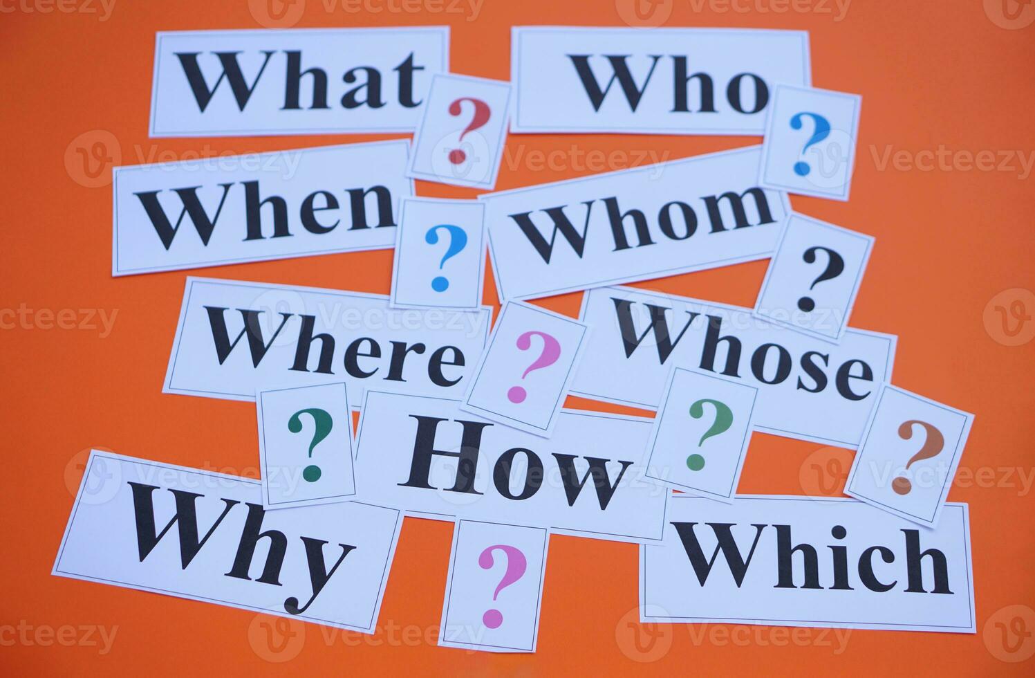 Paper cards with Wh-question words and question marks on orange background. Concept. Teaching aid. Education materials for teach WH- question. Asking questions. Suspicious symbol to find answer. photo