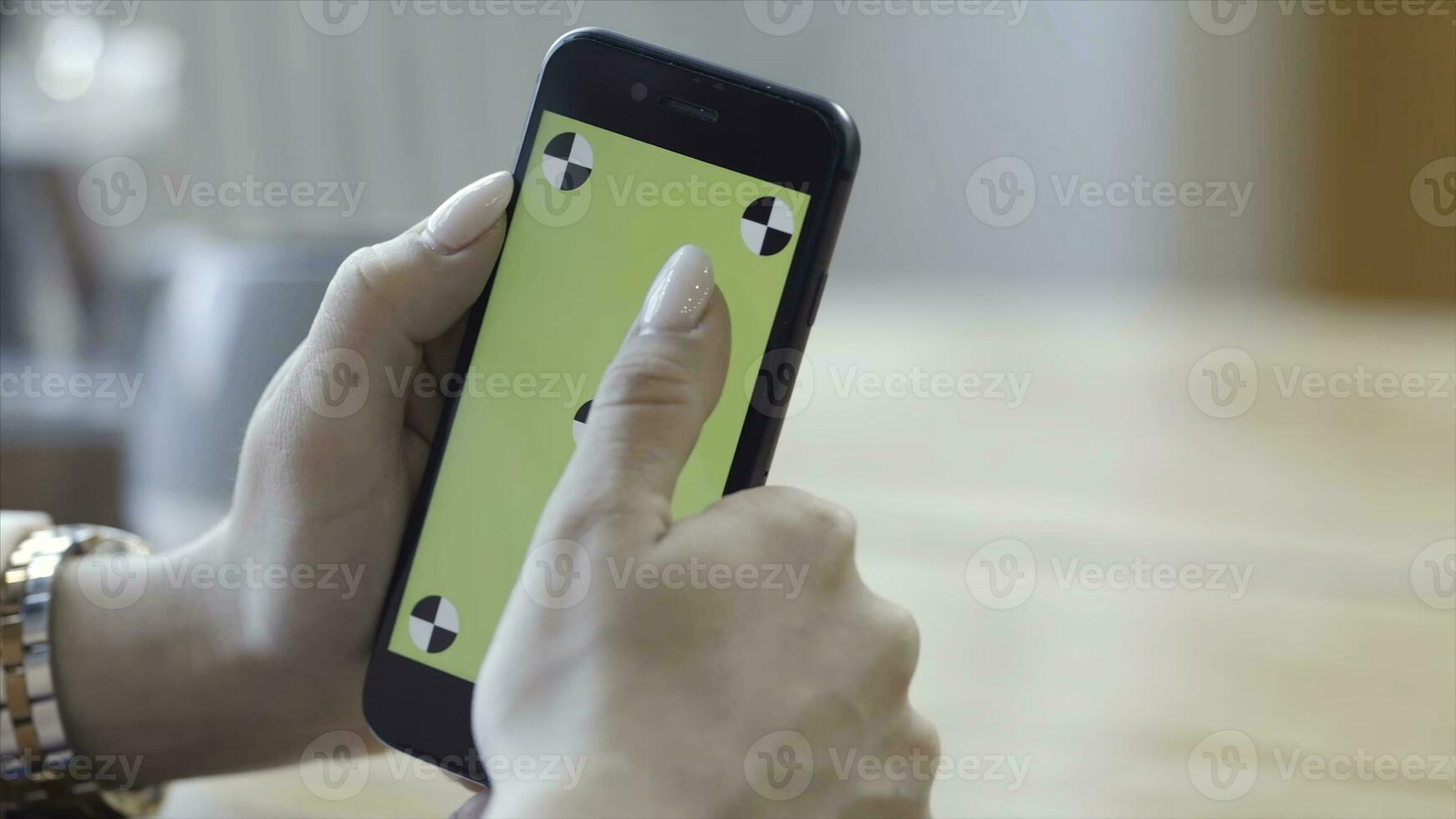 Young woman with beautiful manicure holding iPhone in hands and typing on the chroma key green screen. Stock footage. Technology, mockup and internet concept photo