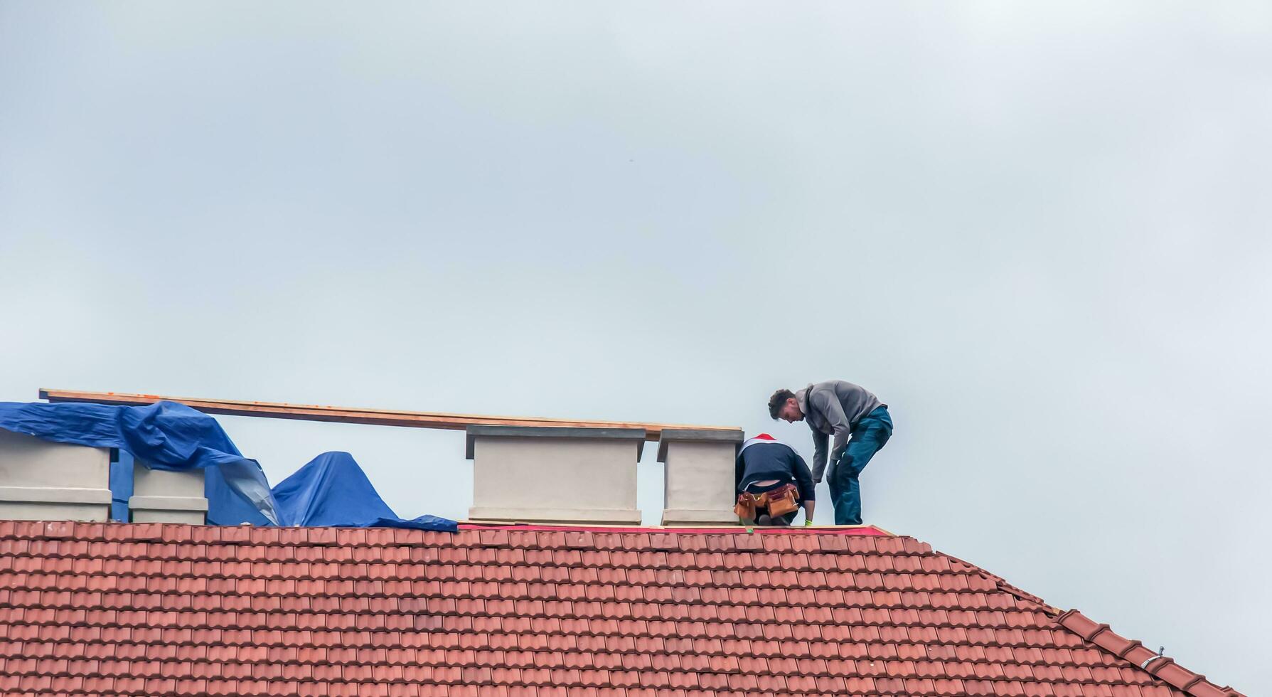 Nitra, Slovakia - 05.15.2023 Handymen repair chimneys on the roof of a house. photo