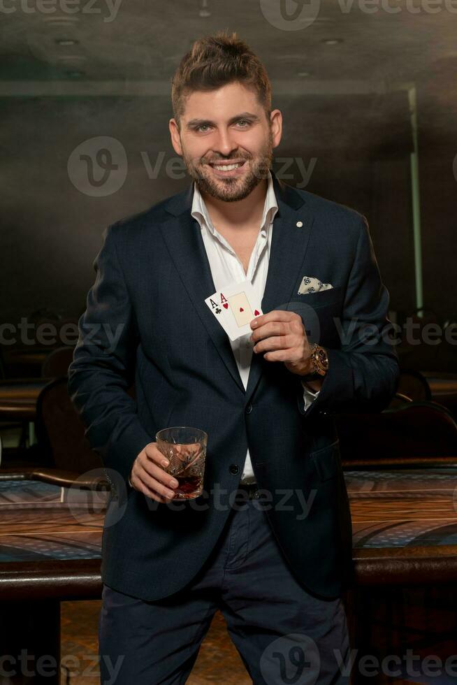 Successful man with two aces in hand celebrating poker win with glass of brandy photo