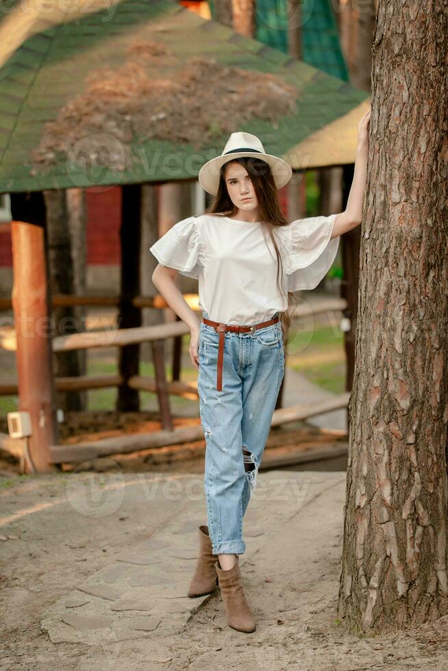 elegante adolescente niña en pie propensión en alto árbol en país inmuebles en verano día foto