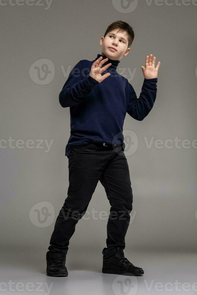 Nice schoolboy is posing at studio over a gray background. photo