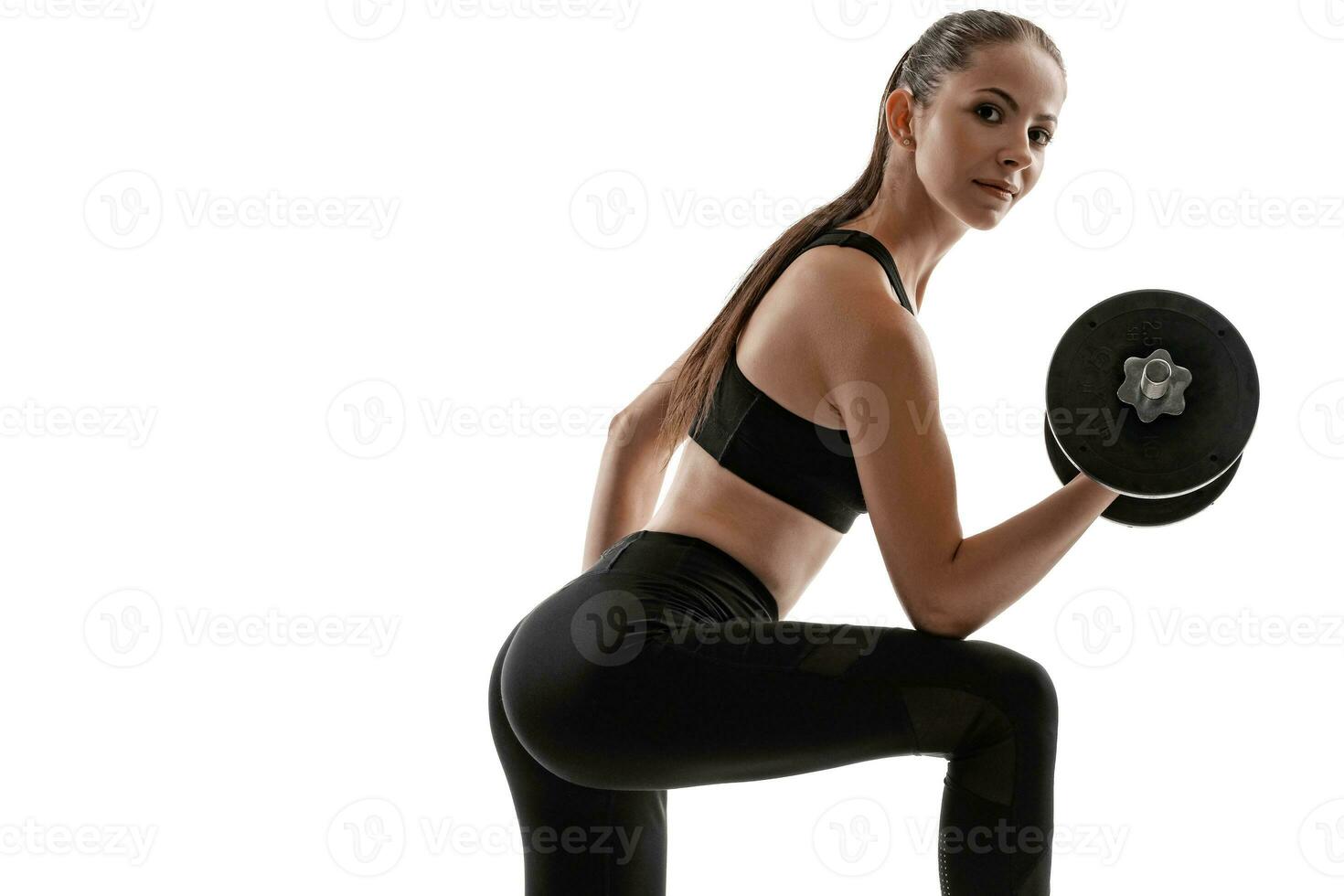 Brunette woman in black leggings, top and sneakers is posing isolated on white. Fitness, gym, healthy lifestyle concept. photo
