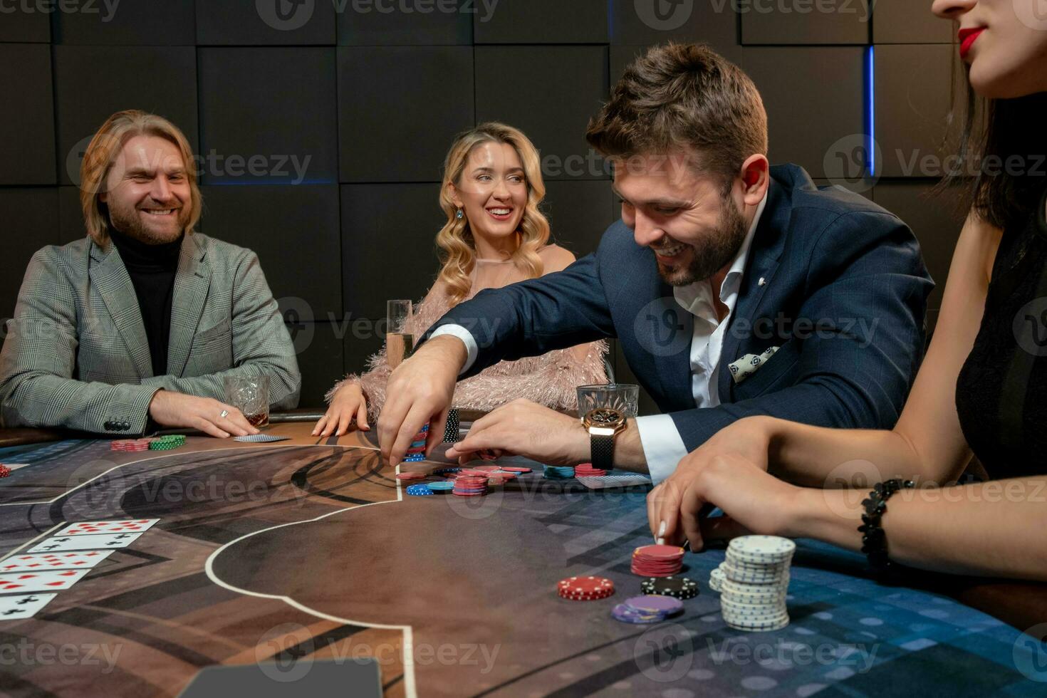 Cheerful bearded guy sitting at poker table in casino and making bet photo