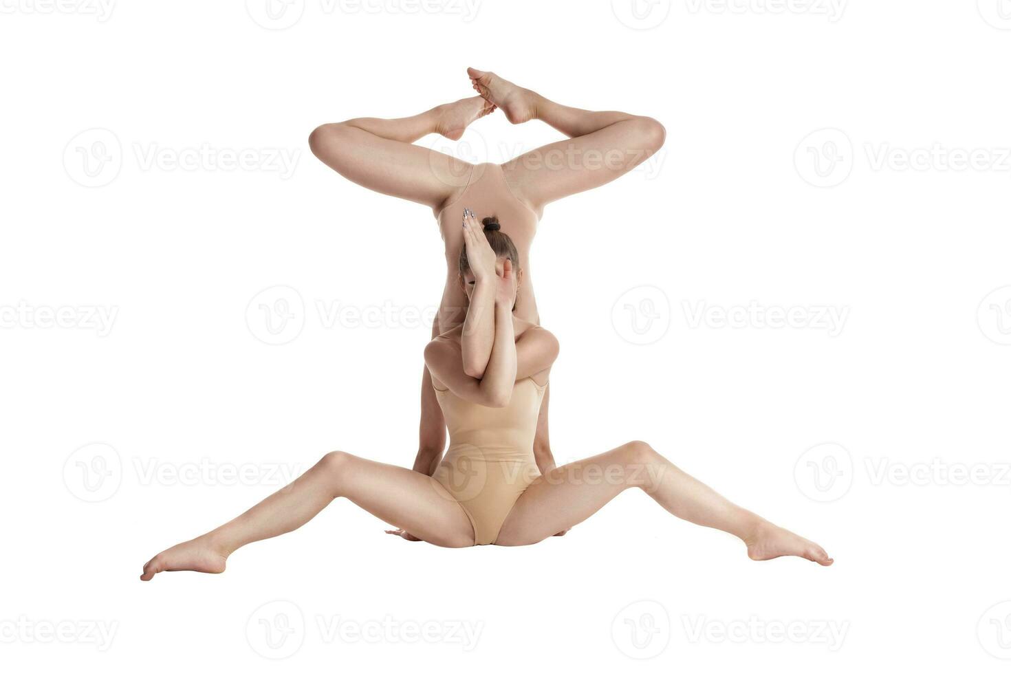 Two flexible girls gymnasts in beige leotards performing complex elements of gymnastics using support, posing isolated on white background. Close-up. photo