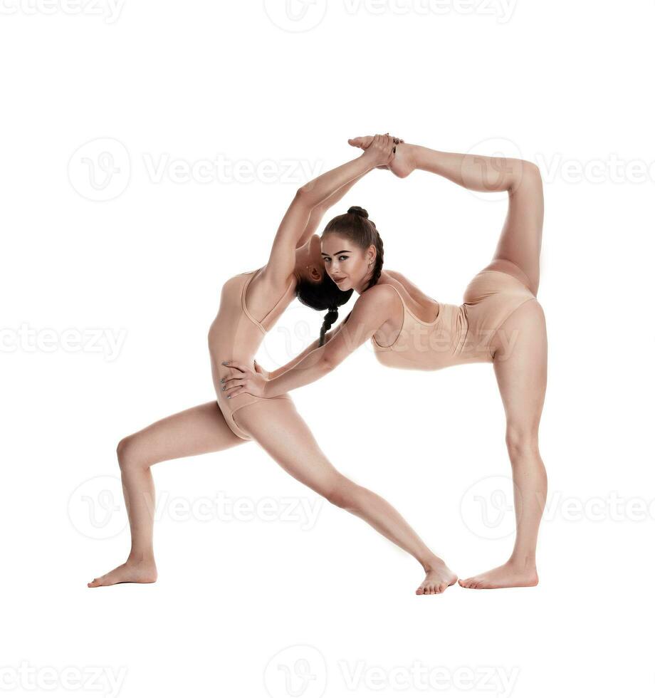 Two flexible girls gymnasts in beige leotards are performing exercises using support and posing isolated on white background. Close-up. photo