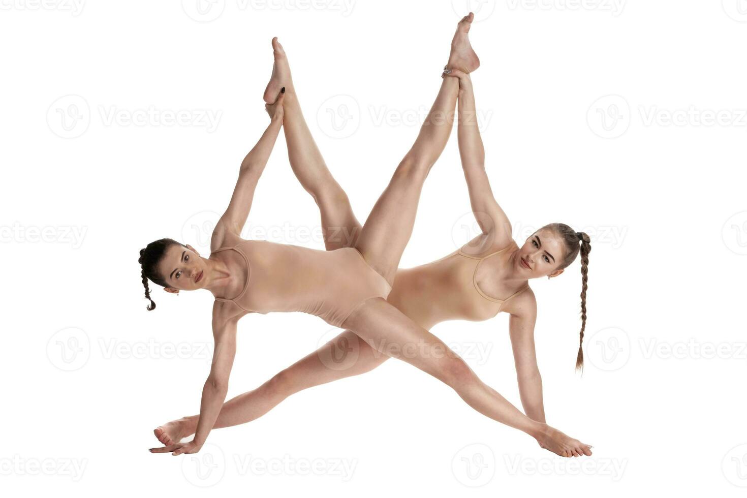 dos flexible muchachas gimnastas en beige leotardos ejecutando complejo elementos de gimnasia utilizando apoyo, posando aislado en blanco antecedentes. de cerca. foto