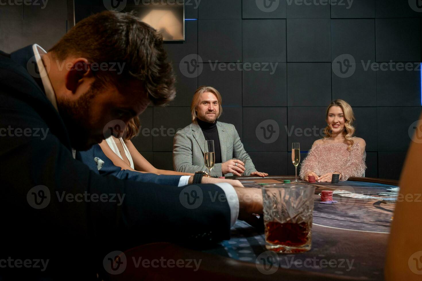 Positive people playing poker at gaming table in casino photo