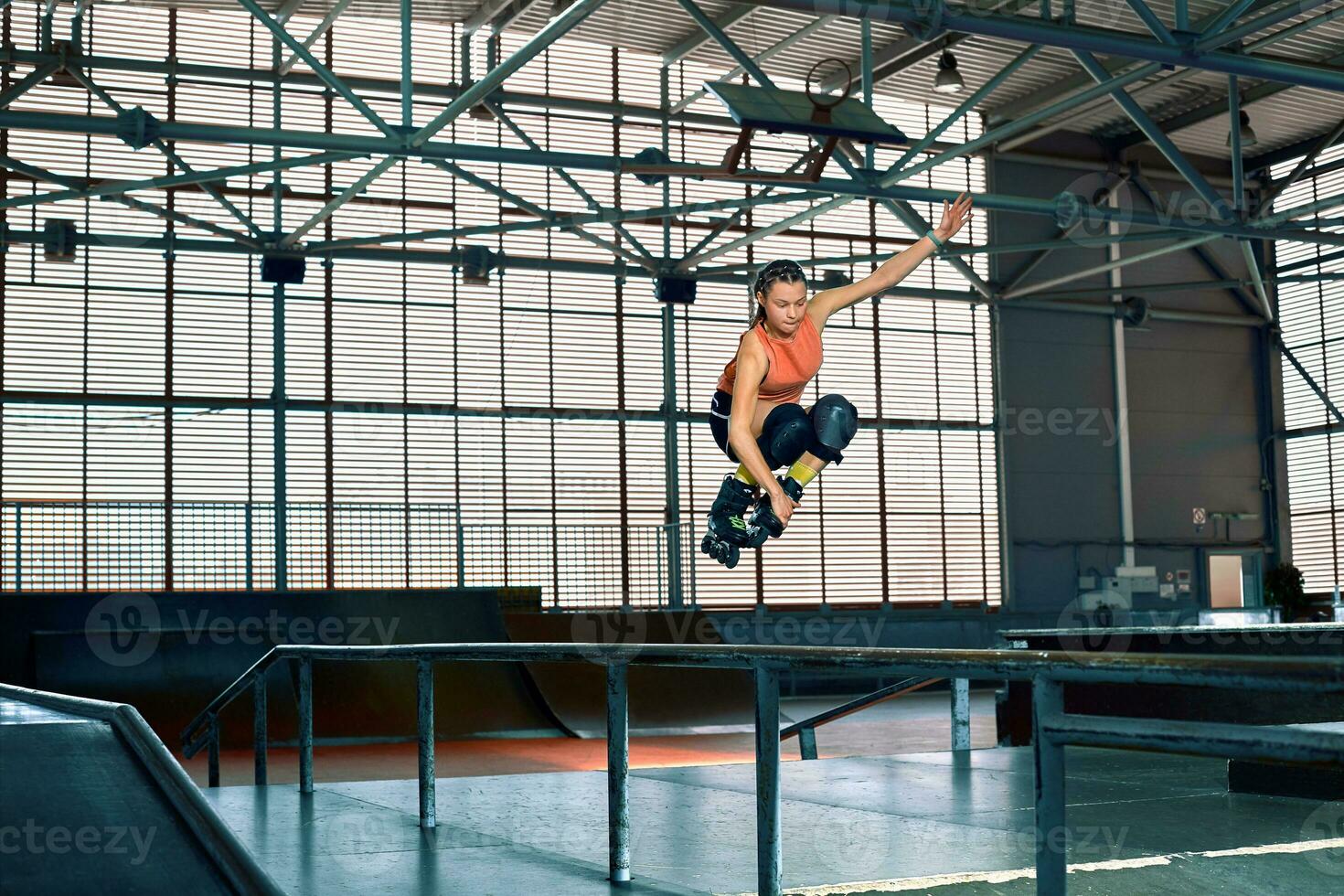 Rollerblader jump high from big air ramp performing trick. Indoors skate park equipment. photo