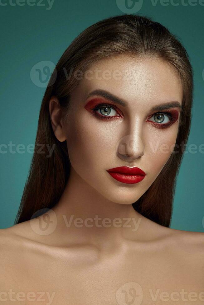 Close-up glamour portrait of a beautiful half-naked model with bright make-up posing over a gray background. photo