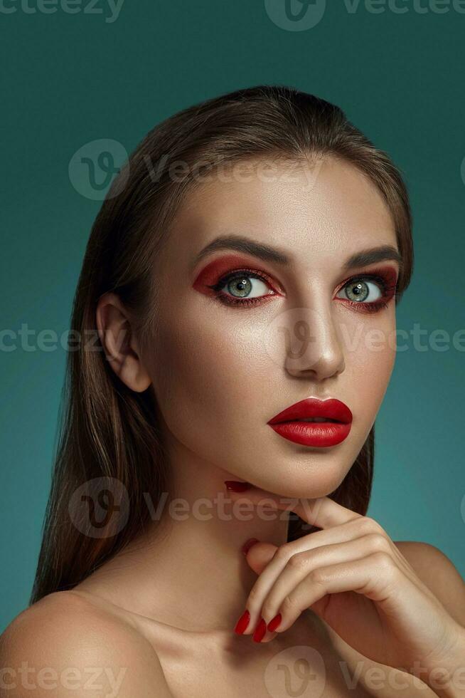 Close-up glamour portrait of a beautiful half-naked model with bright make-up posing over a gray background. photo