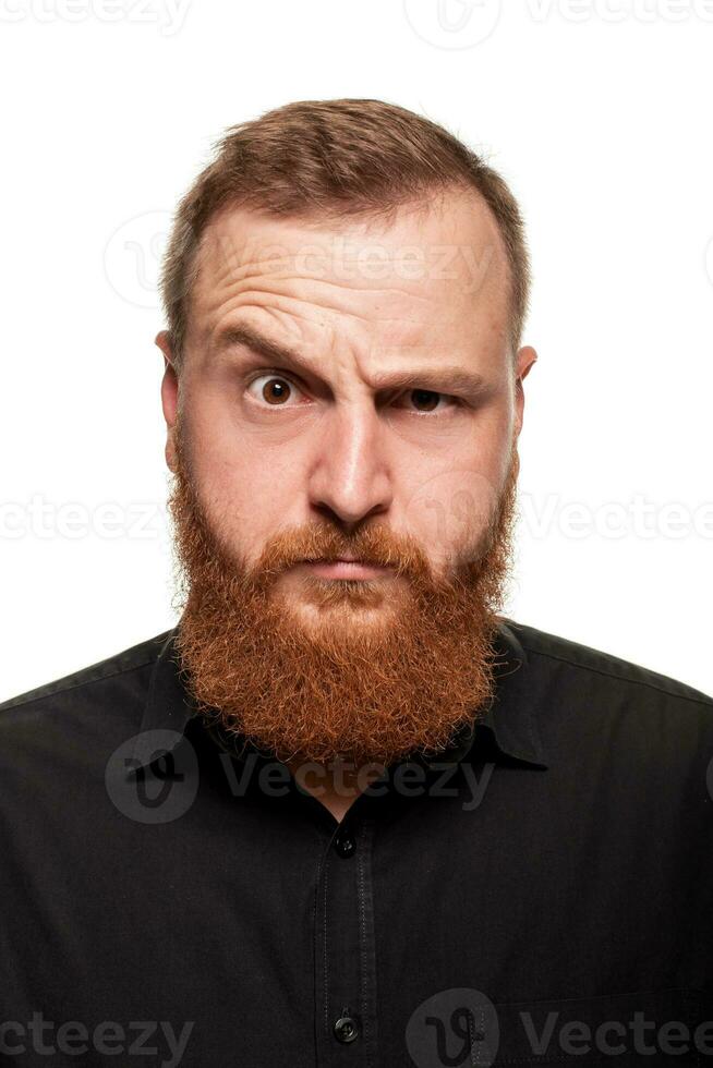 Portrait of a young, chubby, redheaded man in a black shirt making faces at the camera, isolated on a white background photo