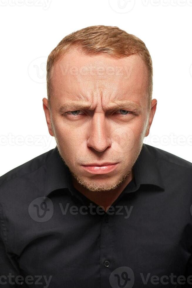 retrato de joven hombre cuestionablemente desconfiadamente mirando con bajado Cejas en blanco antecedentes. foto