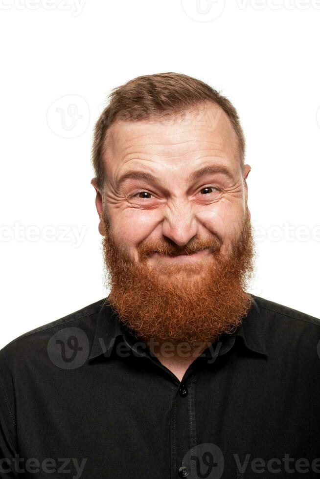 Portrait of a young, chubby, redheaded man in a black shirt making faces at the camera, isolated on a white background photo