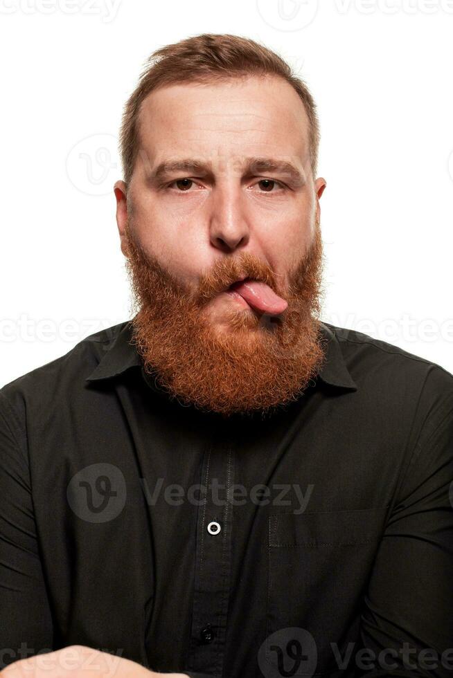 Portrait of a young, chubby, redheaded man in a black shirt making faces at the camera, isolated on a white background photo