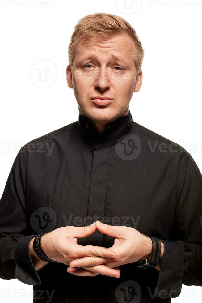 Young blond man in a black shirt, watches and bracelet is making faces, isolated on a white background photo