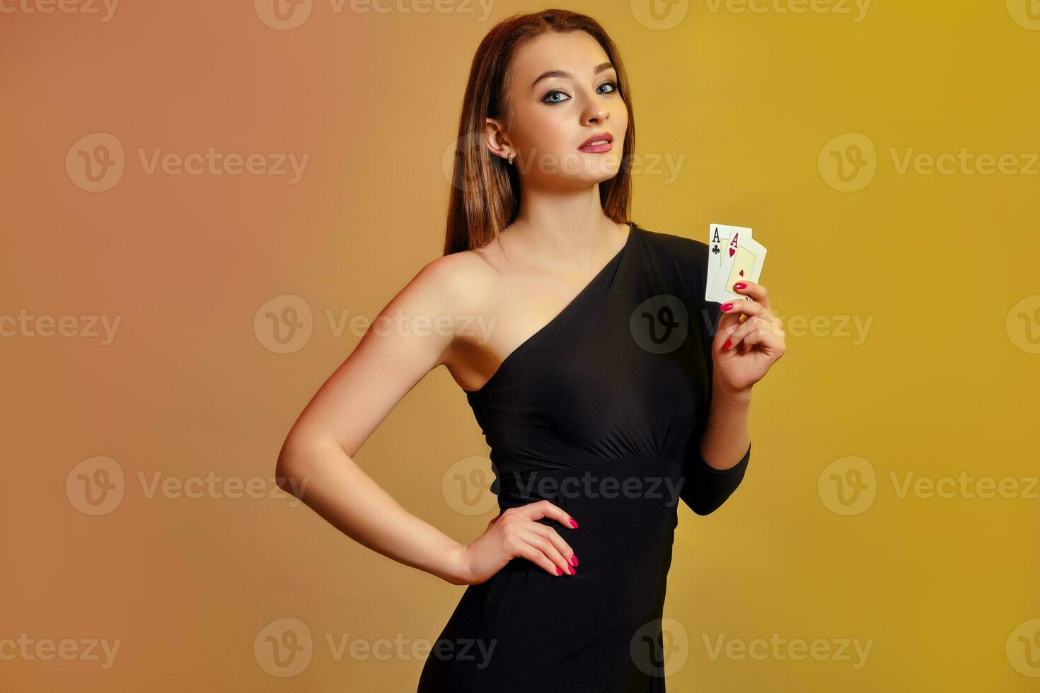 Blonde lady with bright make-up, in black dress is showing two aces, posing against colorful background. Gambling, poker, casino. Close-up. photo