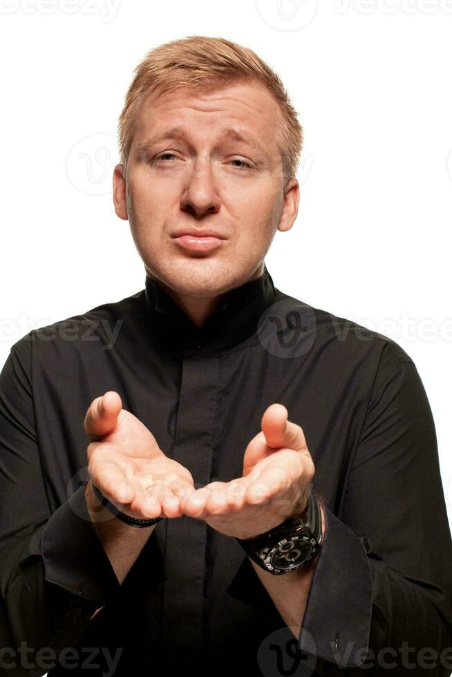 Young blond man in a black shirt, watches and bracelet is making faces, isolated on a white background photo