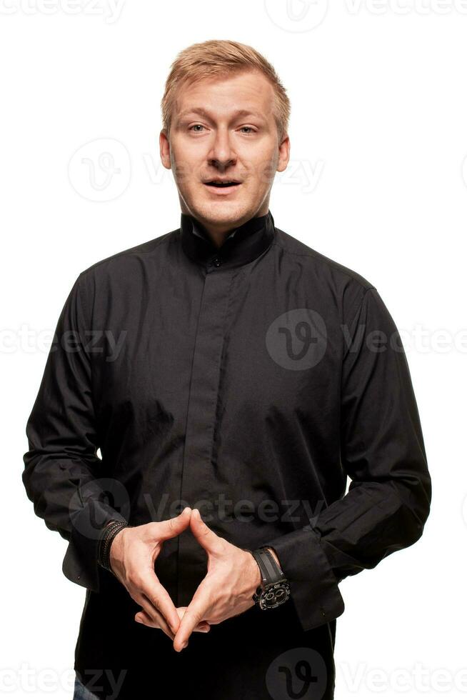 Young blond man in a black shirt, watches and bracelet is making faces, isolated on a white background photo