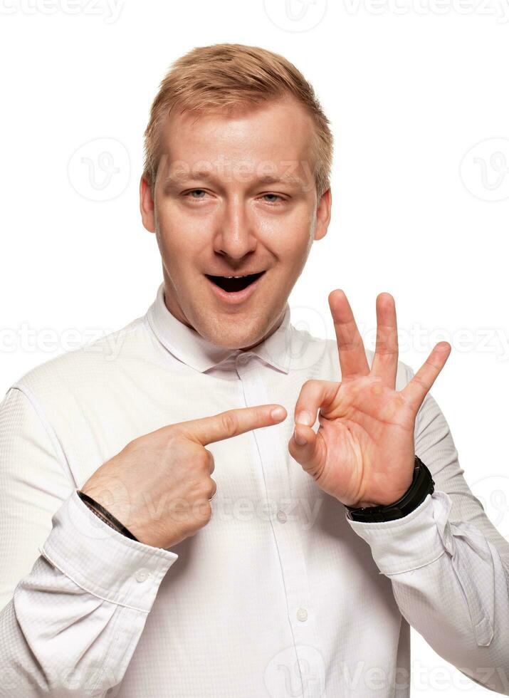 Imposing, young, blond man in a white shirt is grimacing while standing isolated on a white background photo