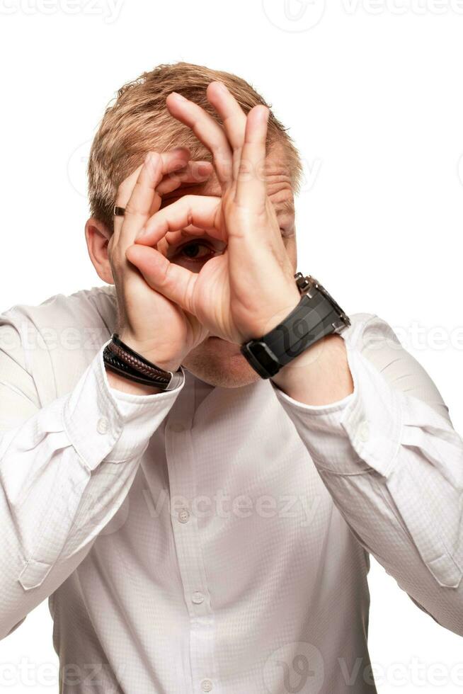 Imposing, young, blond man in a white shirt is grimacing while standing isolated on a white background photo