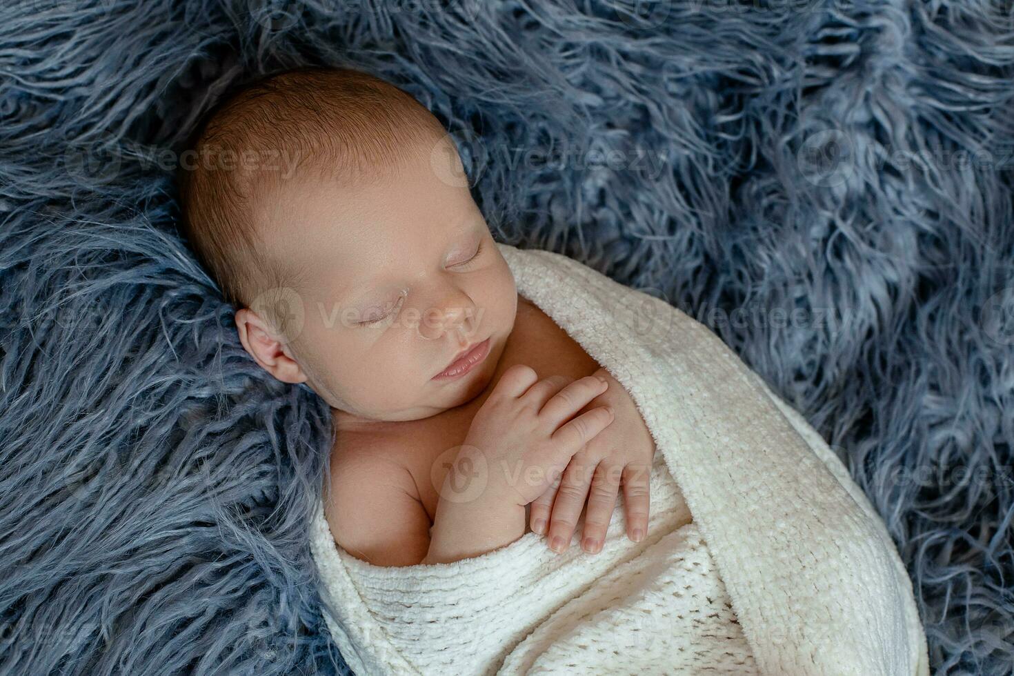 Newborn baby boy in bed. New born child sleeping under a white knitted blanket. Children sleep. photo