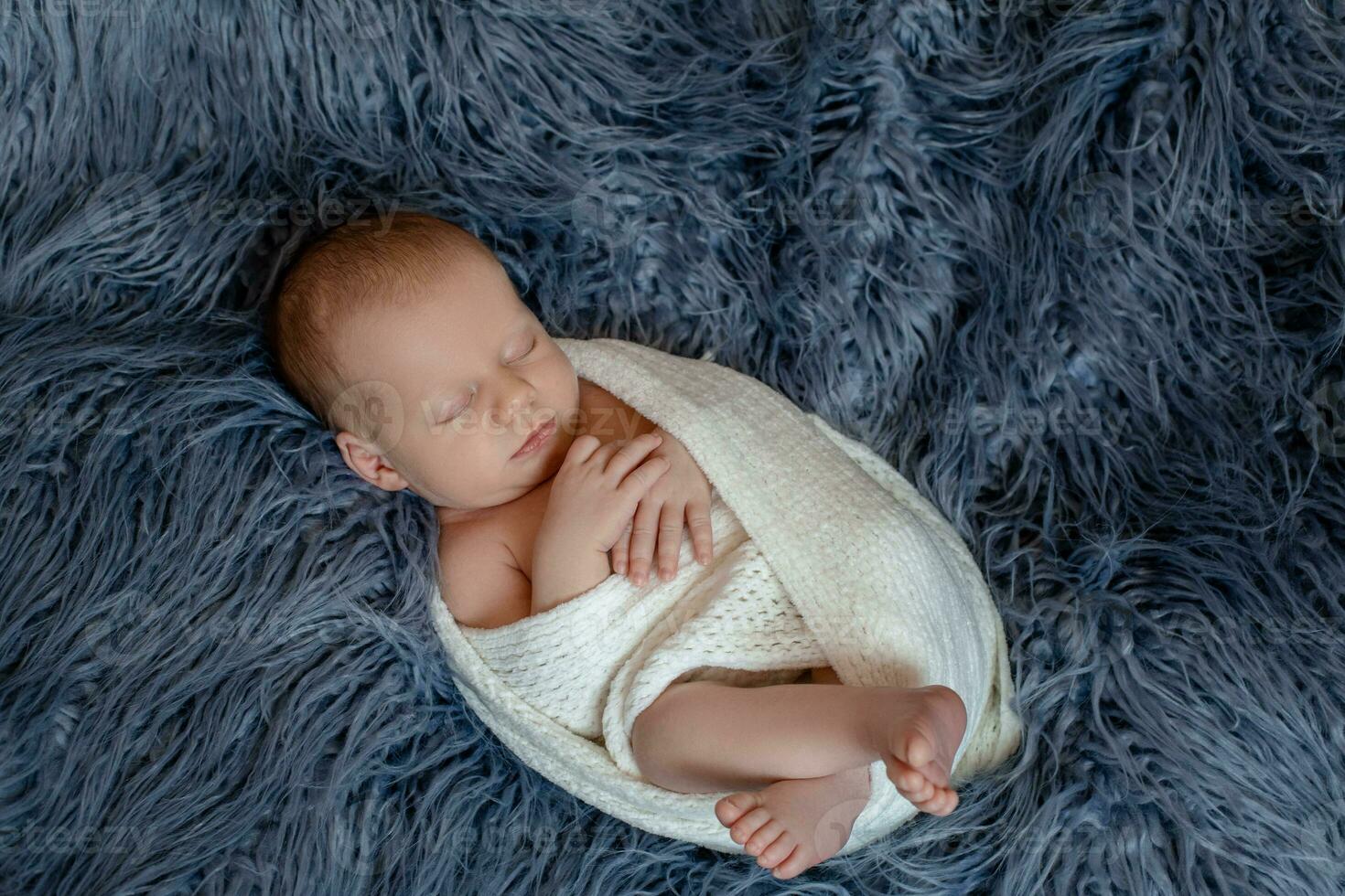 Newborn baby boy in bed. New born child sleeping under a white knitted blanket. Children sleep. photo