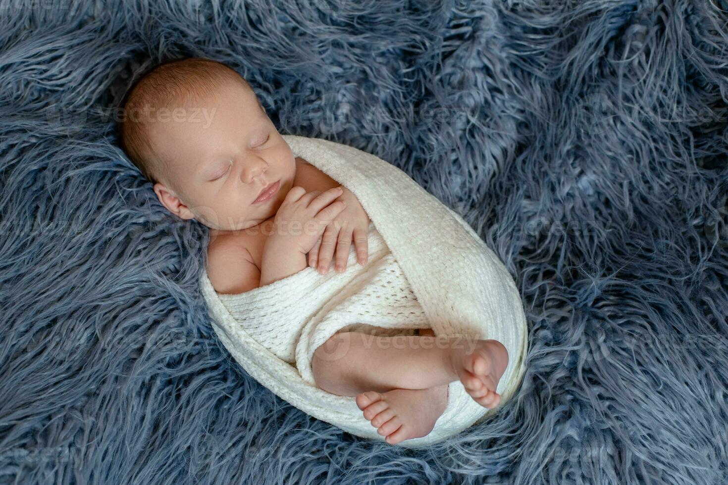 Newborn baby boy in bed. New born child sleeping under a white knitted blanket. Children sleep. photo