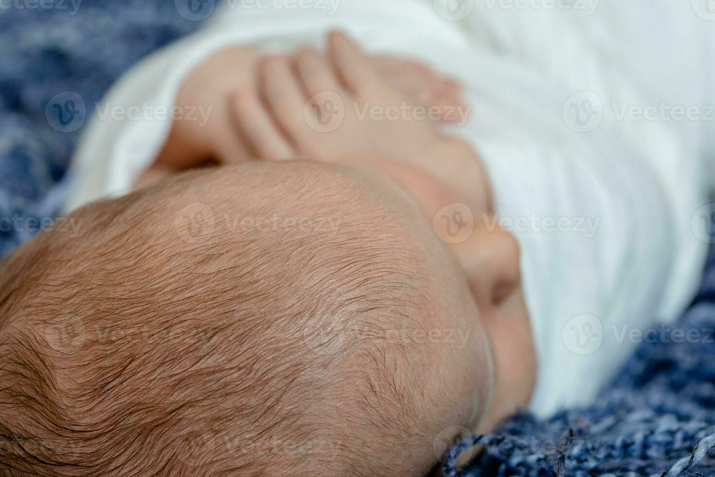 recién nacido - bebé, cara de cerca. el dormido recién nacido chico debajo un blanco de punto cobija mentiras en el azul pelo. foto