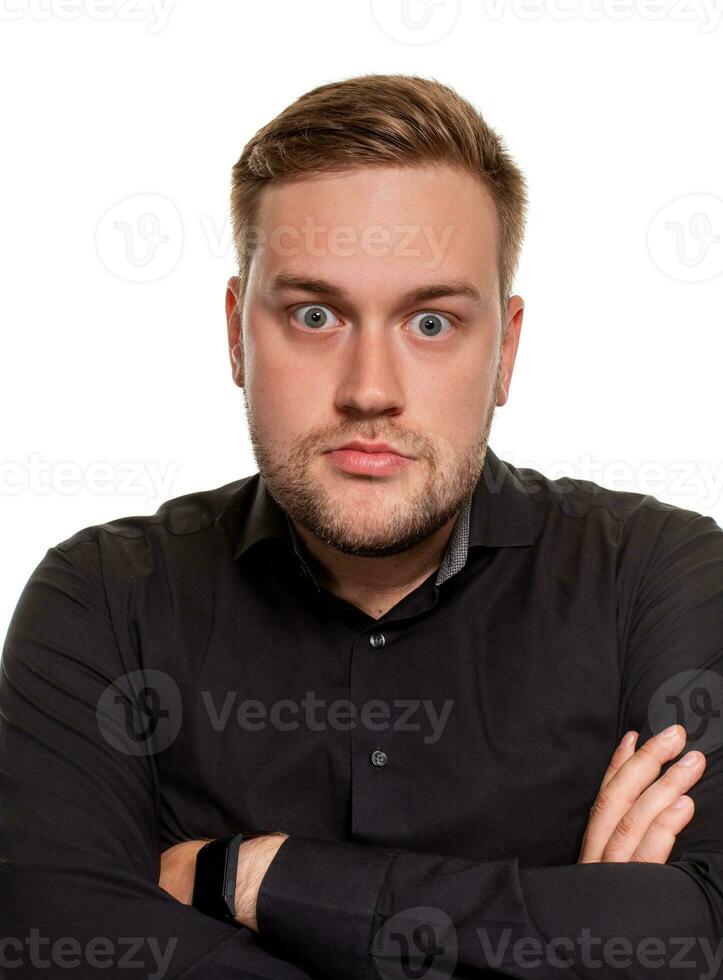 Serious or unhappy young man holding hands crossed and looking at camera in dislike on white background. photo