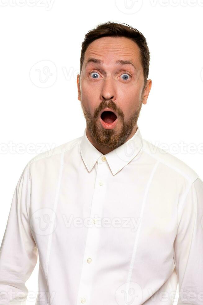 Unbelievable news. Young adult crazy man with opened mouth looking at camera. Studio shot, white background photo