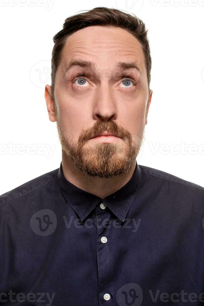 Portrait of a handsome, unshaven man, dressed in a dark blue shirt, standing against a white background. Self confident man. photo