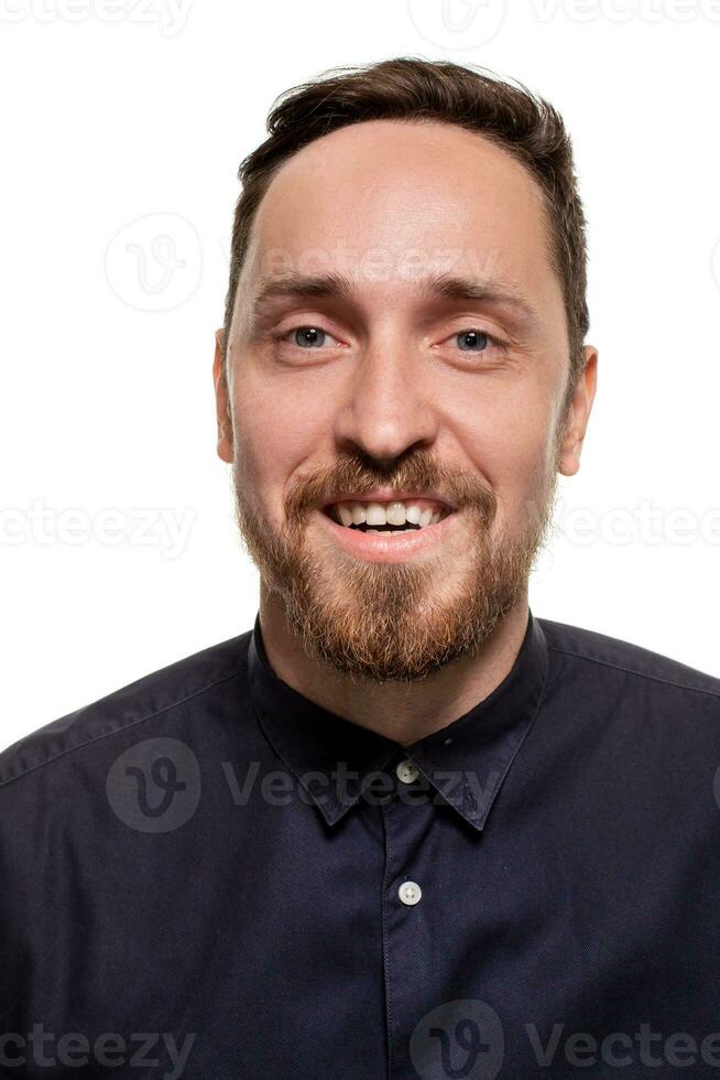 retrato de un elegante, sin afeitar hombre, vestido en un oscuro azul camisa, en pie en contra un blanco antecedentes. yo confidente hombre. foto