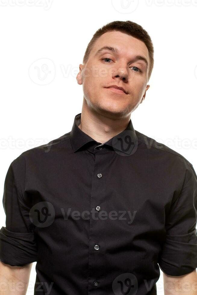 Handsome young man in a black shirt is making faces, while standing isolated on a white background photo