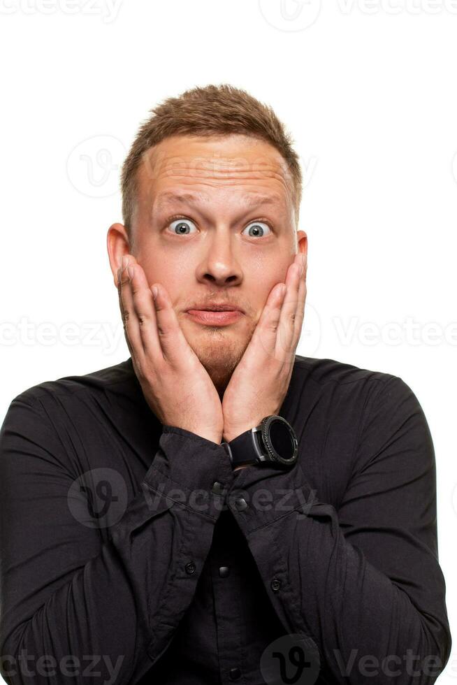 Portrait of young man in black shirt holding palms near cheek photo