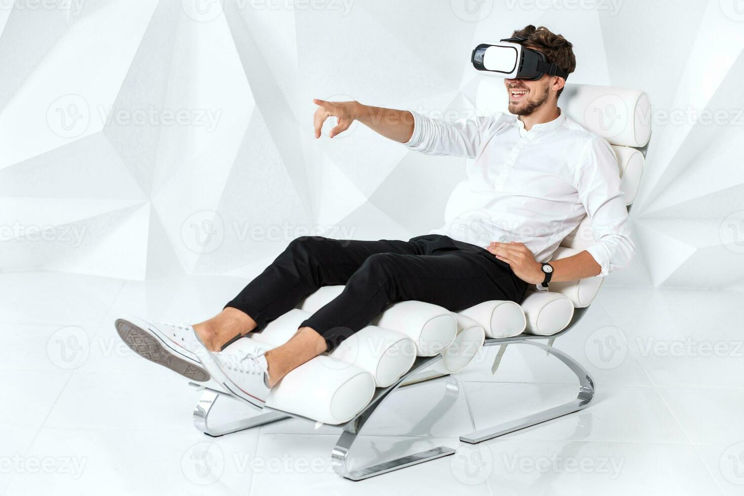 Excited young man is getting experience using VR-headset glasses of virtual reality gesticulating with his hands photo