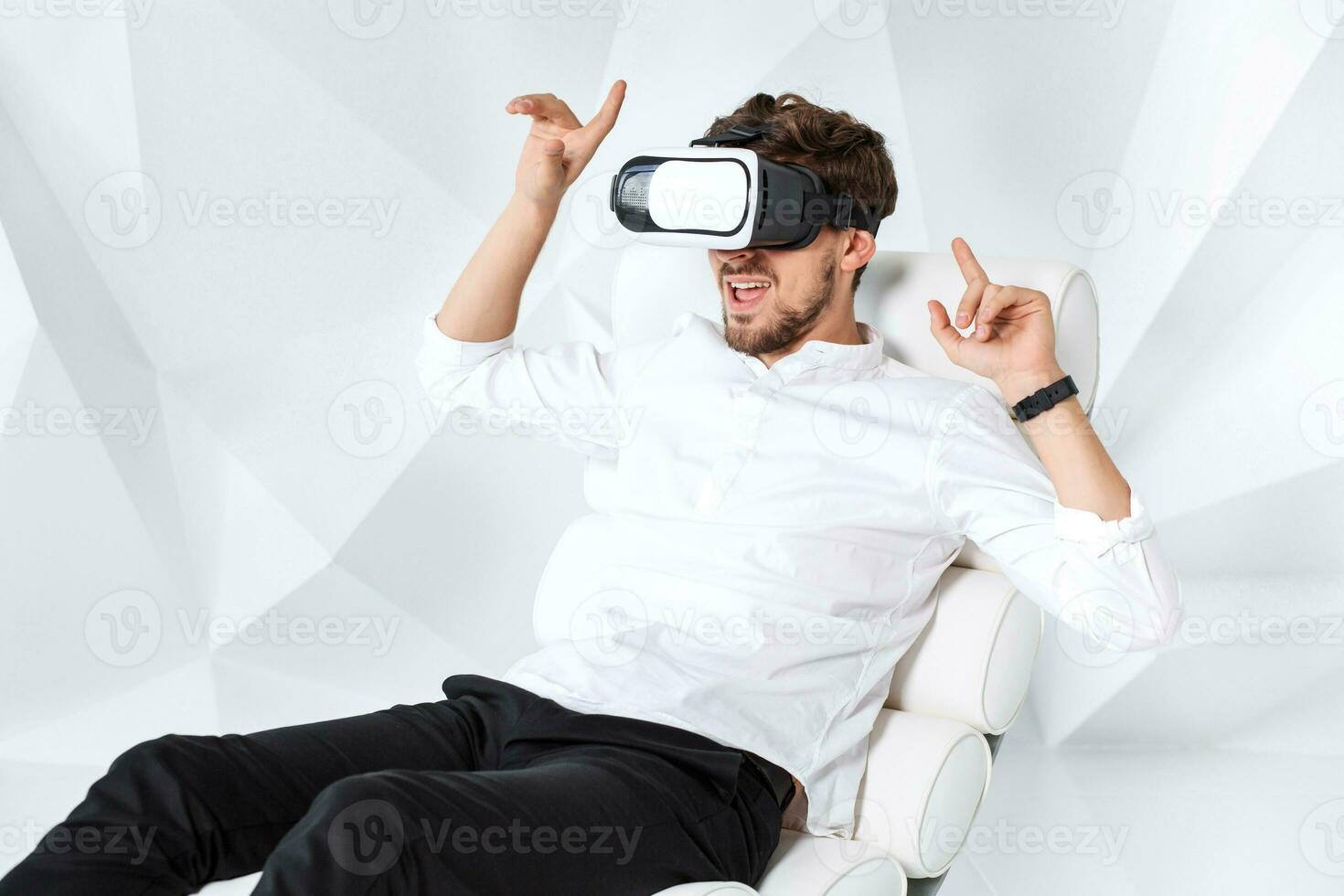 Excited young man is getting experience using VR-headset glasses of virtual reality gesticulating with his hands photo
