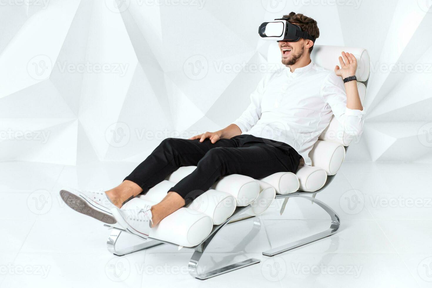 Excited young man is getting experience using VR-headset glasses of virtual reality gesticulating with his hands photo