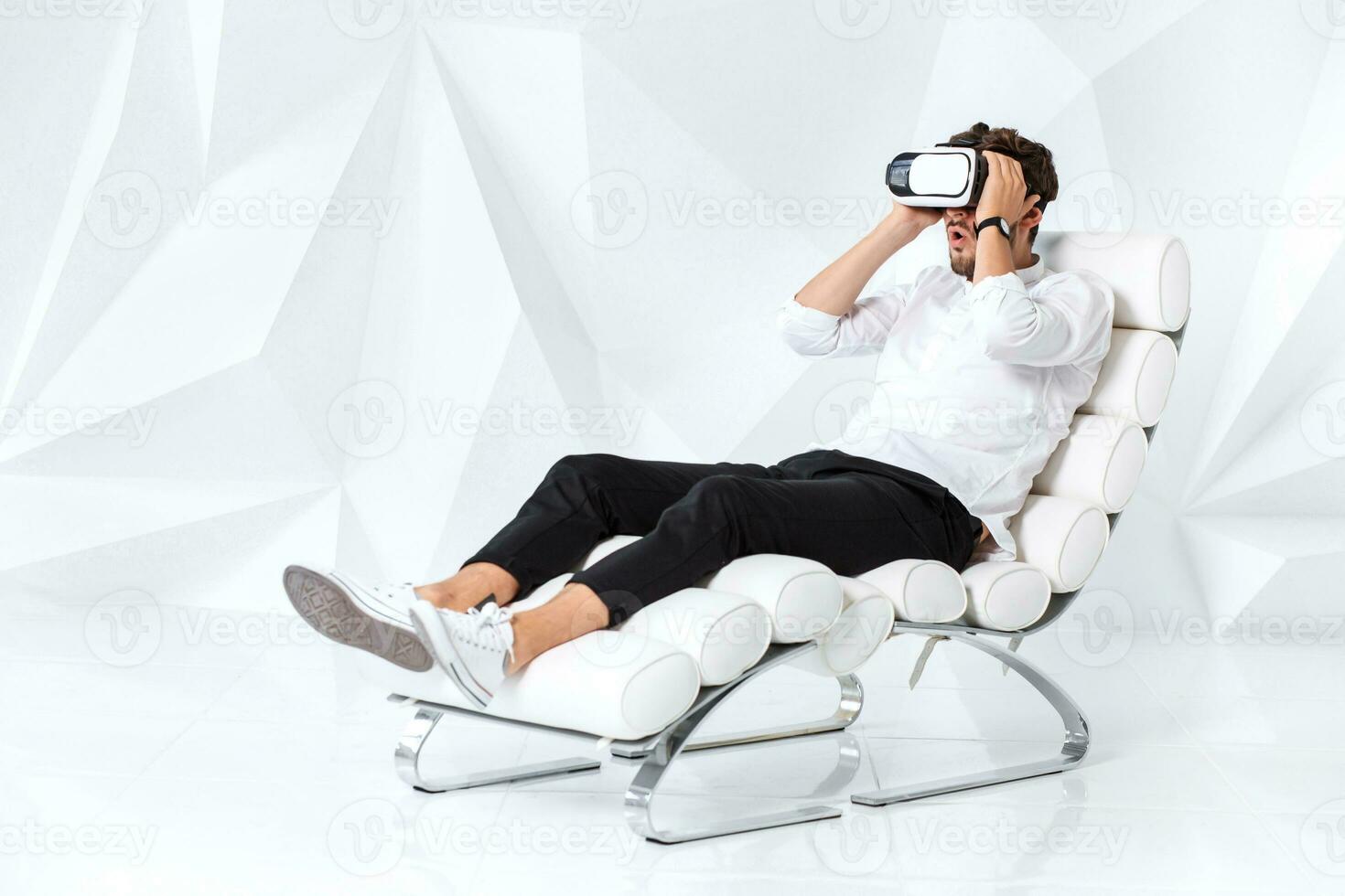 Excited young man is getting experience using VR-headset glasses of virtual reality gesticulating with his hands photo