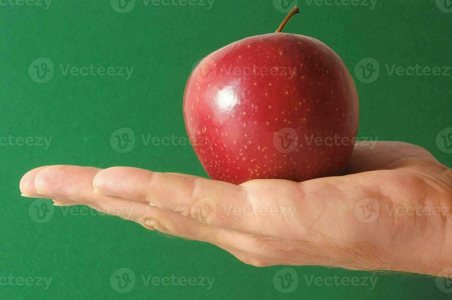 un mano participación un manzana en un verde antecedentes foto