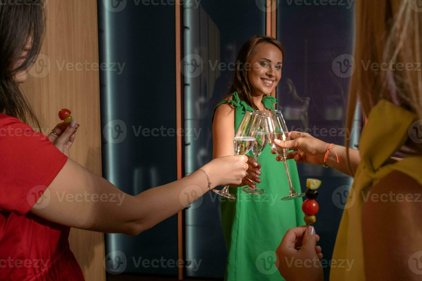 Smiling girl clinking glasses of champagne with her female friends photo