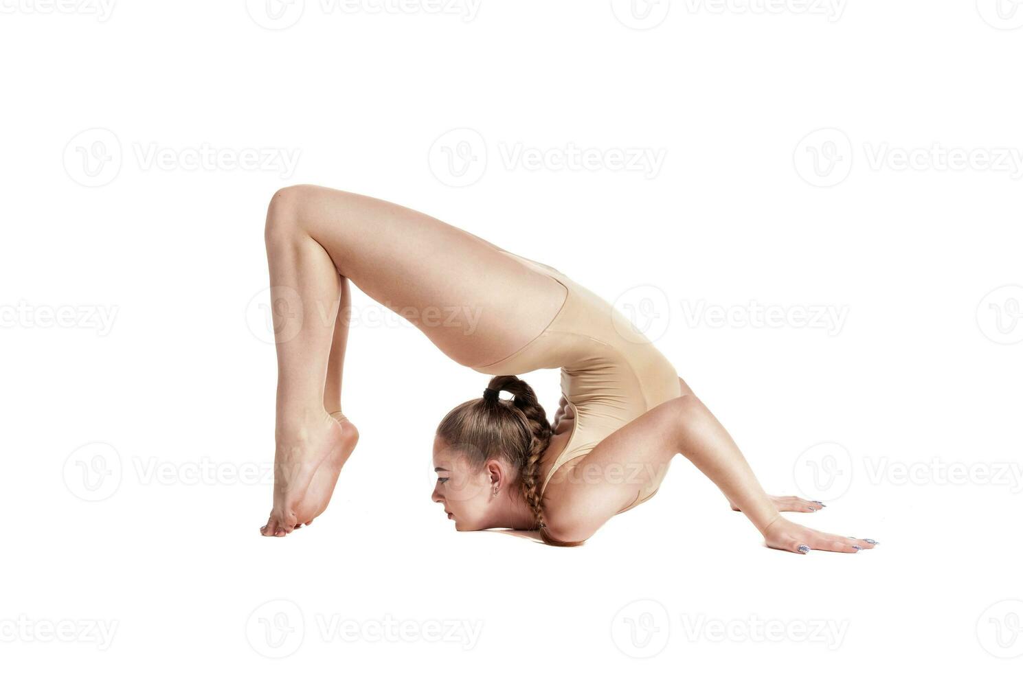 Flexible girl gymnast in beige leotard is performing complex elements of gymnastics while posing isolated on white background. Close-up. photo
