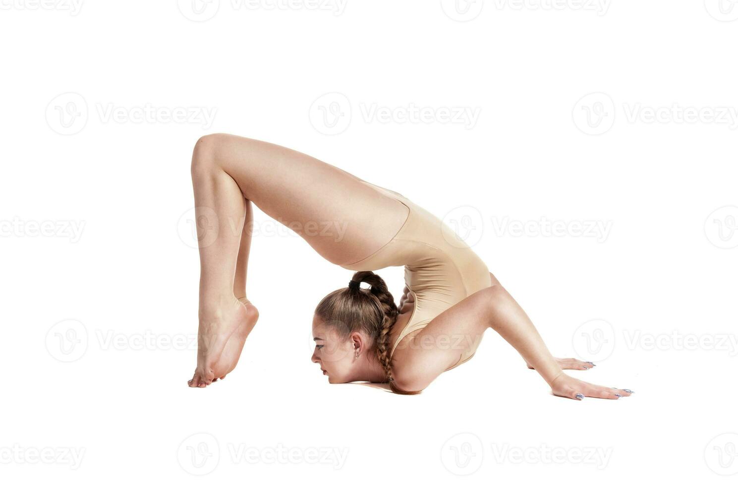 flexible niña gimnasta en beige leotardo es ejecutando complejo elementos de gimnasia mientras posando aislado en blanco antecedentes. de cerca. foto