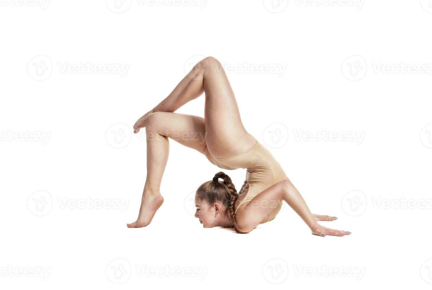 Flexible girl gymnast in beige leotard is performing complex elements of gymnastics while posing isolated on white background. Close-up. photo